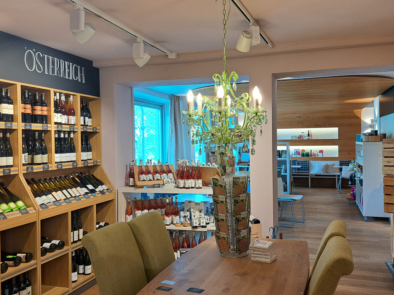 Blick aus der Weinabteilung in den Speiseraum von Mayr's Bistro mit einem Kronleuchter in der Mitte.